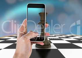 Hand with phone against chess piece and blue bokeh