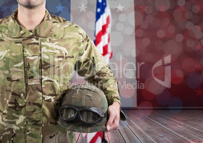 Part of a soldier holding a helmet against an american flag background
