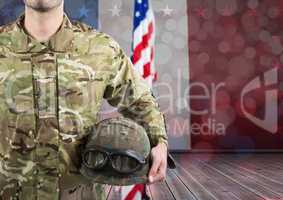Part of a soldier holding a helmet against an american flag background