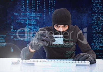 Hacker holding a credit card and typing on a keyboard in front of digital background