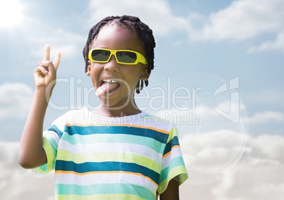 Boy in sunglasses making peace sign against sky with flare