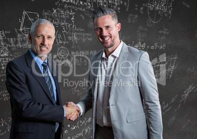 Business men shaking hands against grey wall with math doodles