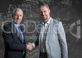 Business men shaking hands against grey wall with math doodles