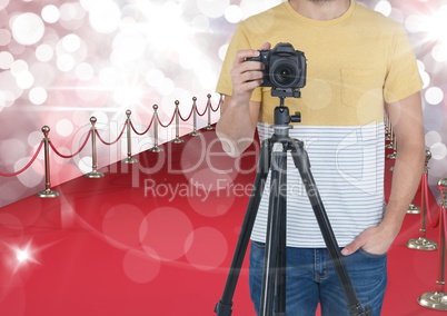 photographer with camera on tripod in the red carpet. Red and white bokeh background and flares ever