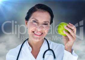 Female doctor with apple against clouds and flares