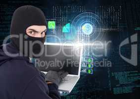 Hacker looking the lens and using a laptop in front of digital background