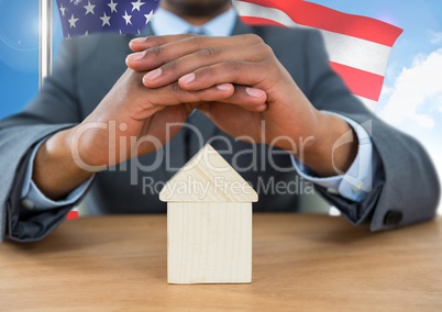 Business man covering a 3D house against american flag