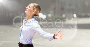 Business woman arms outstretched against blurry street with flare