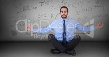 Business man meditating in grey room with math doodles
