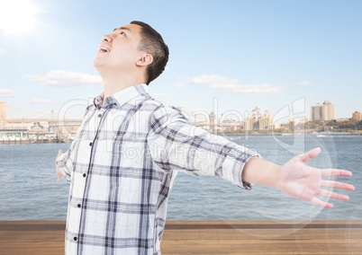 Man with arms outstretched against water and skyline with flare