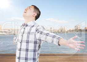 Man with arms outstretched against water and skyline with flare