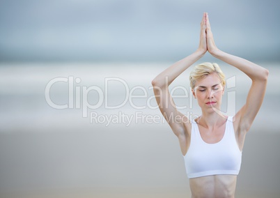 Woman meditating against blurry beach