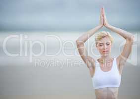 Woman meditating against blurry beach