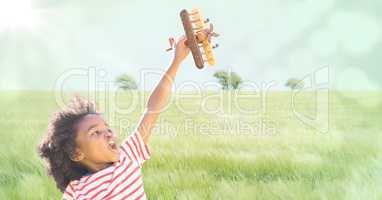 Boy with toy plane against meadow with flare