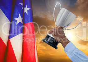 Part of a man holding a cup by a fluttering american flag