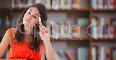 College student with pen against blurry bookshelf