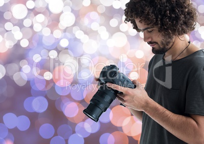 young photographer looking the photos on the camera. Blue, purple and white bokeh background