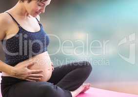 Pregnant woman meditating against blurry blue brown background