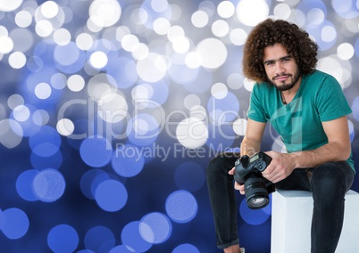 3d photographer with camera on the hands, sitting. Blue bokeh background
