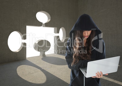 Woman hacker working on laptop in front of background with a 3D puzzle hole
