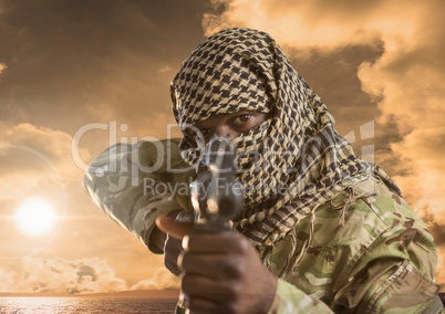 Military pointing with a gun against sunset