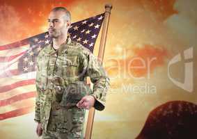 Soldier holding his helmet in front of american background
