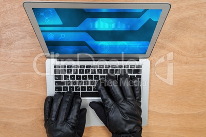 Hacker wearing gloves using a grey laptop