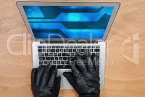 Hacker wearing gloves using a grey laptop