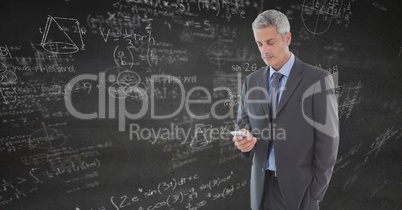 Business man texting against grey wall with math doodles