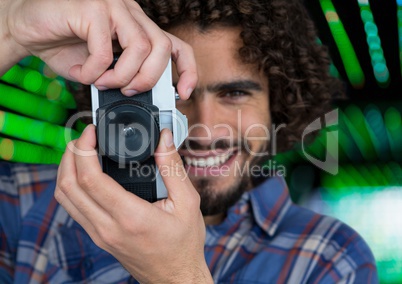 happy photographer taking a photo with vintage camera. Green blurred lights behind