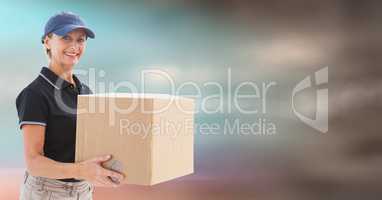 Middle aged delivery woman with box against blurry blue brown background