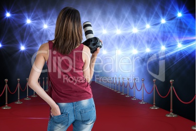 Woman from behind on a red carpet with camera on her hands