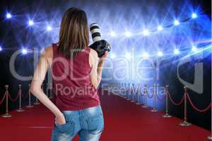Woman from behind on a red carpet with camera on her hands