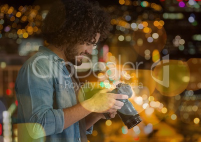 photographer looking to the photos on camera, in the city at night (with blurred lights)