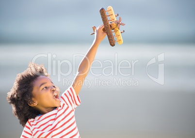 Boy with toy plane against blurry beach