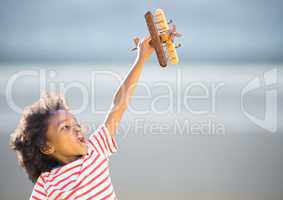 Boy with toy plane against blurry beach
