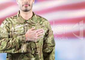 Part of a soldier with hand on the heart against fluttering american flag