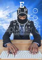 Businessman with hood typing on keyboard in front of blue background with digital letters