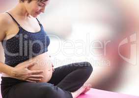 Pregnant woman meditating against blurry red and white abstract background