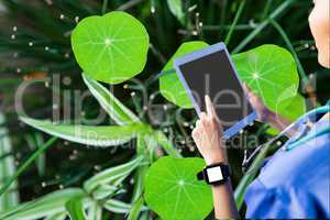 Model with tablet against 3d leaves