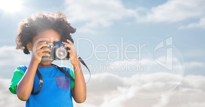 Boy with camera against sky with flare