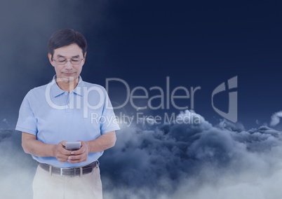 Man texting in darkness with clouds in background
