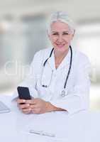 Doctor at desk with phone against white blurred windows