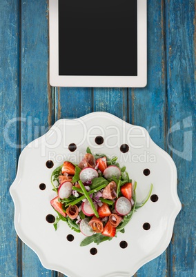 Tablet on blue wooden desk with food and copy space