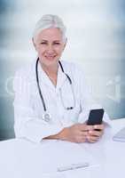 Doctor at desk holding phone against blurry blue wood panel