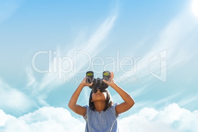 Girl looking through binoculars against sky