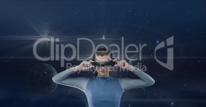 Woman in VR headset looking against blue sky with planets and flares