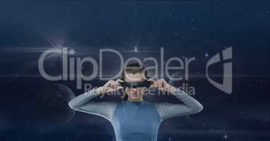 Woman in VR headset looking against blue sky with planets and flares