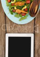 Tablet on wooden desk with food and copy space