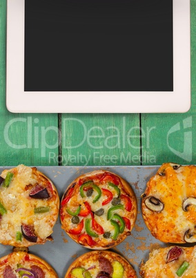 Tablet on green wooden desk with food and copy space
